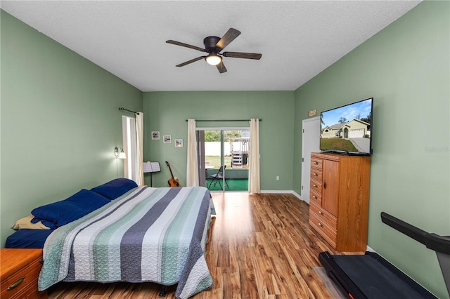 bedroom with a textured ceiling, wood finished floors, a ceiling fan, baseboards, and access to exterior