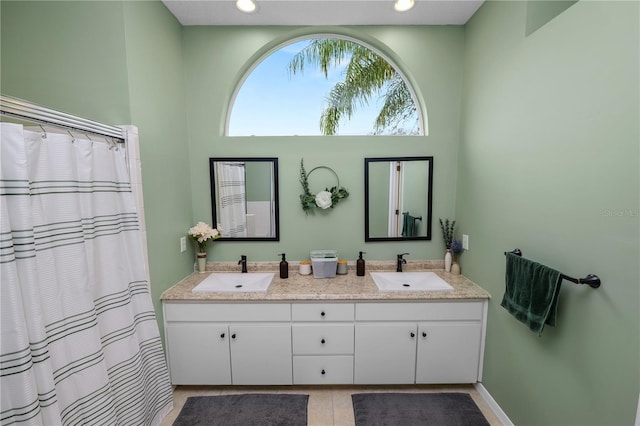 full bath with double vanity, baseboards, a sink, and recessed lighting