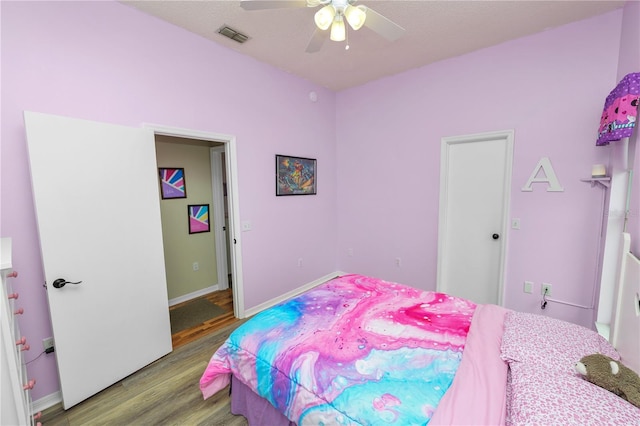 bedroom with baseboards, wood finished floors, visible vents, and a ceiling fan