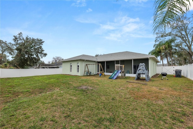 rear view of house featuring a yard, a fenced backyard, a sunroom, and stucco siding