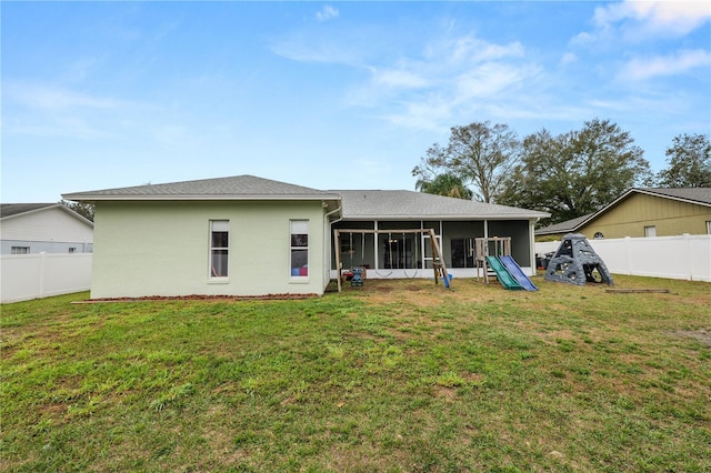 rear view of property with a lawn, a fenced backyard, a sunroom, and stucco siding