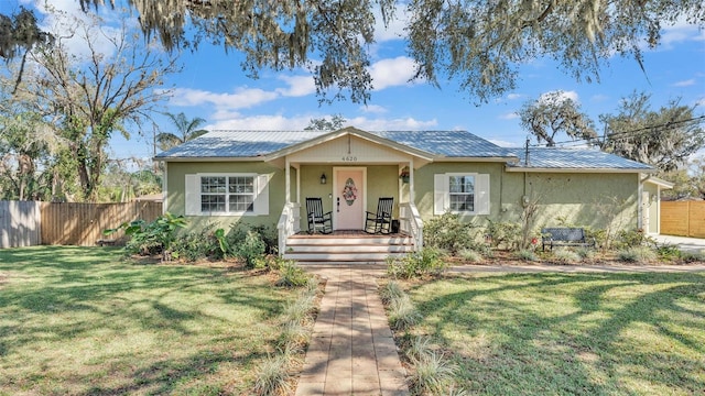 view of front of property with metal roof, a garage, fence, stucco siding, and a front yard