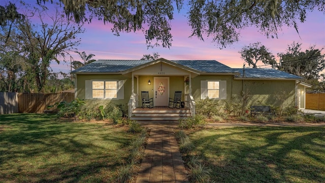 view of front facade with a garage, a yard, fence, and stucco siding