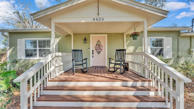 doorway to property with covered porch and stucco siding