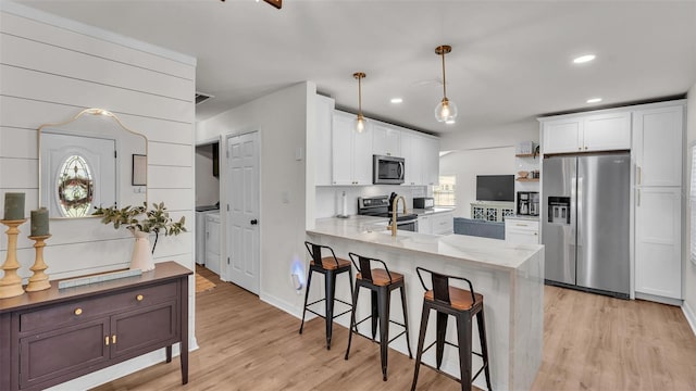 kitchen with a peninsula, white cabinets, stainless steel appliances, and pendant lighting