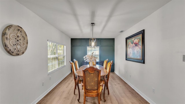 dining room featuring light wood-style flooring, visible vents, and baseboards