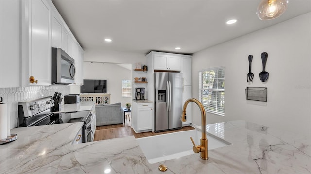 kitchen featuring recessed lighting, white cabinets, appliances with stainless steel finishes, light stone countertops, and open shelves