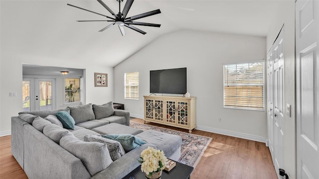 living area featuring light wood finished floors, vaulted ceiling, a wealth of natural light, and french doors