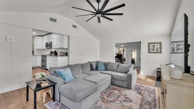 living area with light wood-type flooring, lofted ceiling, and visible vents