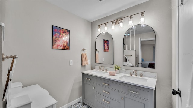 bathroom featuring double vanity, ensuite bath, baseboards, and a sink