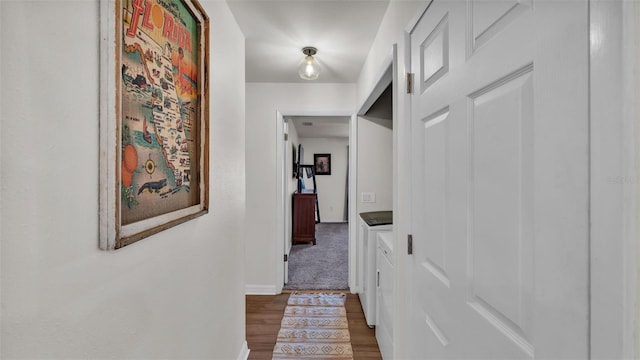 corridor featuring wood finished floors, baseboards, and separate washer and dryer