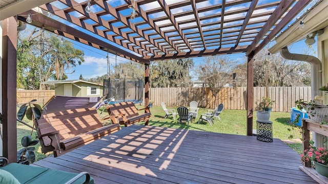 deck with a fenced backyard, a trampoline, a lawn, and a pergola