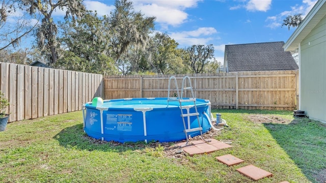 view of swimming pool featuring a lawn, a fenced backyard, and a fenced in pool