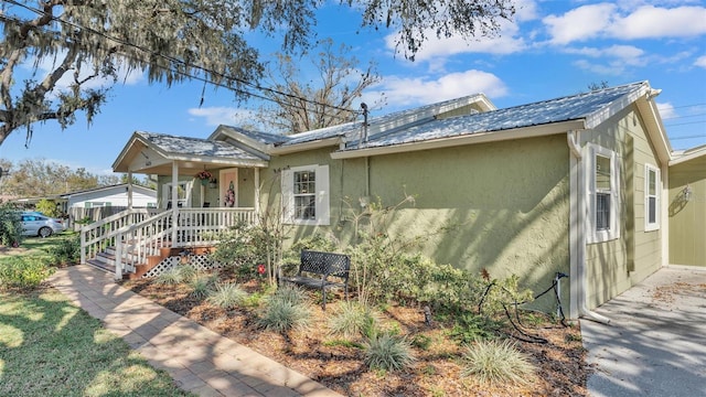 view of front of property featuring covered porch, metal roof, and stucco siding