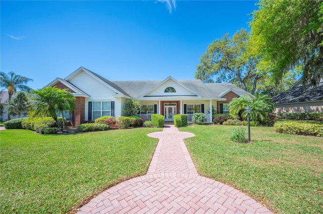 view of front of property with brick siding, a porch, a front lawn, and french doors