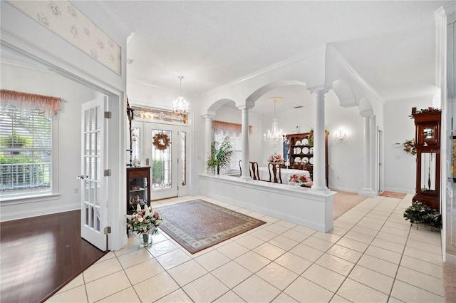 foyer with arched walkways, light tile patterned floors, ornamental molding, and decorative columns