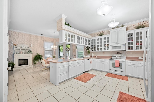 kitchen with wallpapered walls, white appliances, ornamental molding, a peninsula, and a sink