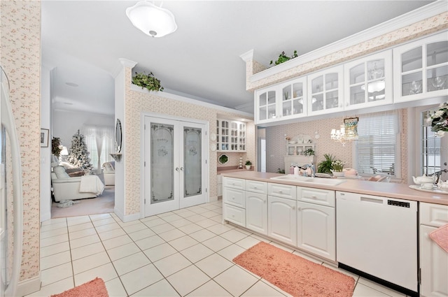 kitchen with crown molding, glass insert cabinets, a sink, dishwasher, and wallpapered walls