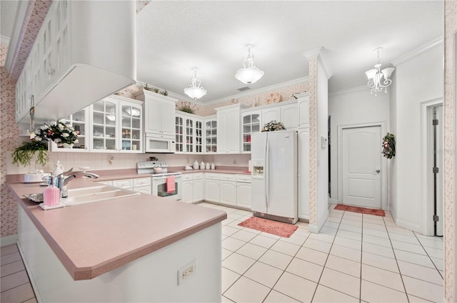 kitchen featuring white appliances, light tile patterned floors, ornamental molding, a peninsula, and a sink