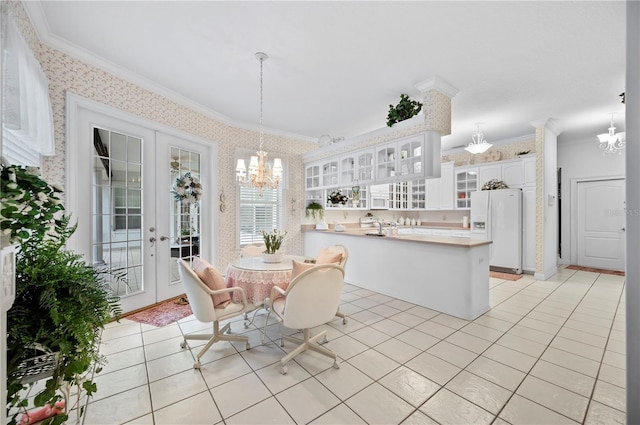 dining area with wallpapered walls, light tile patterned floors, ornamental molding, an inviting chandelier, and french doors