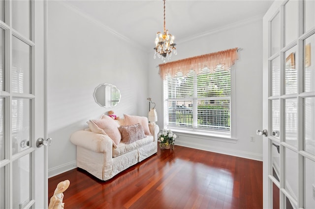 living area with baseboards, an inviting chandelier, wood finished floors, and crown molding