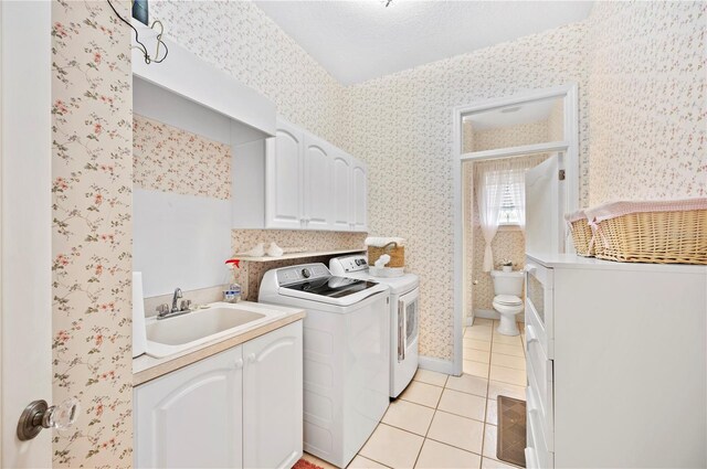 laundry area featuring light tile patterned floors, a sink, separate washer and dryer, and wallpapered walls