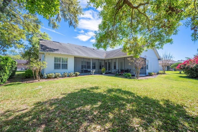 back of property with a yard, a sunroom, and stucco siding