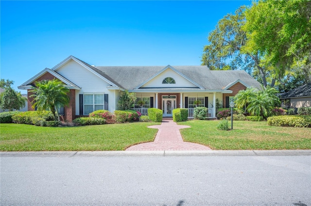 view of front facade featuring covered porch, brick siding, and a front yard