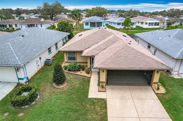 view of front of home featuring a garage, concrete driveway, stucco siding, a residential view, and a front yard