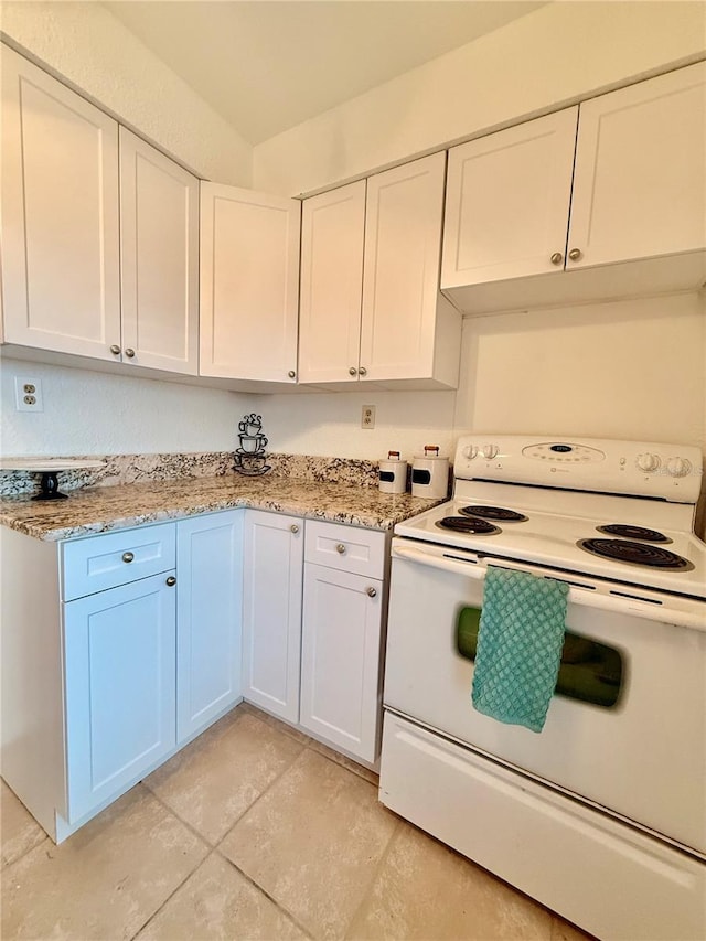 kitchen featuring light stone counters, white cabinets, and electric range