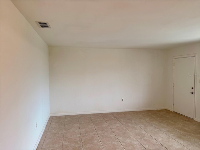 spare room featuring light tile patterned flooring, visible vents, and baseboards