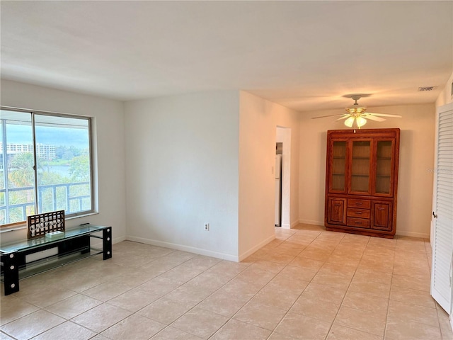 spare room featuring light tile patterned floors, visible vents, baseboards, and a ceiling fan