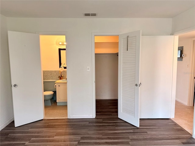 bedroom with dark wood-style floors, a spacious closet, a closet, and visible vents