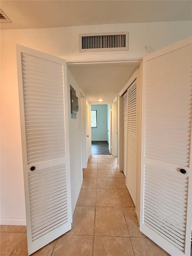 corridor featuring visible vents, baseboards, and light tile patterned flooring