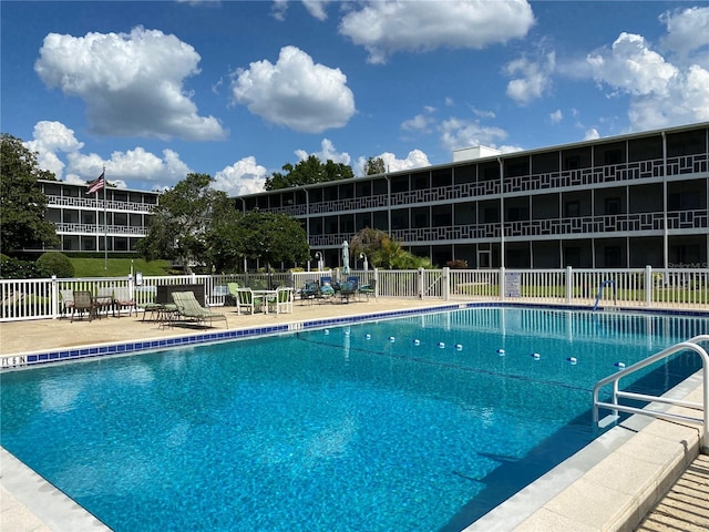 pool with a patio area and fence