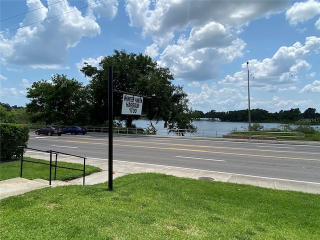 view of street with a water view, sidewalks, and curbs