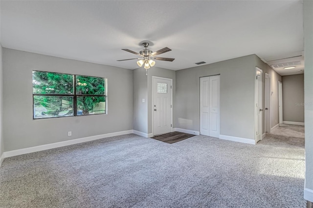 carpeted spare room featuring a ceiling fan, visible vents, and baseboards