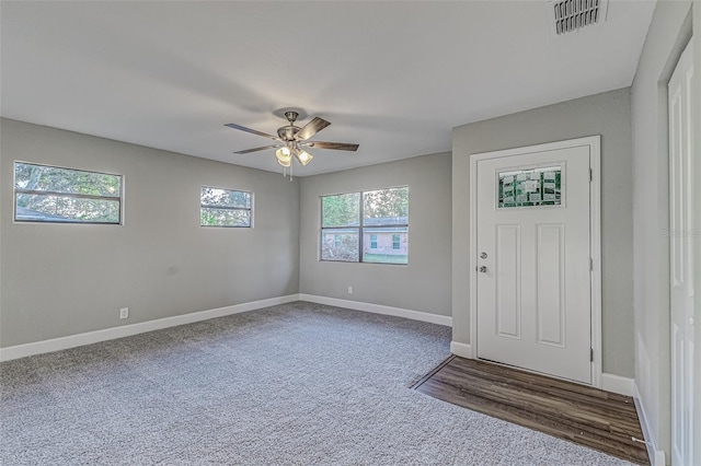 foyer featuring ceiling fan, dark colored carpet, visible vents, and baseboards