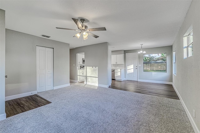 interior space featuring ceiling fan with notable chandelier, dark carpet, visible vents, and baseboards