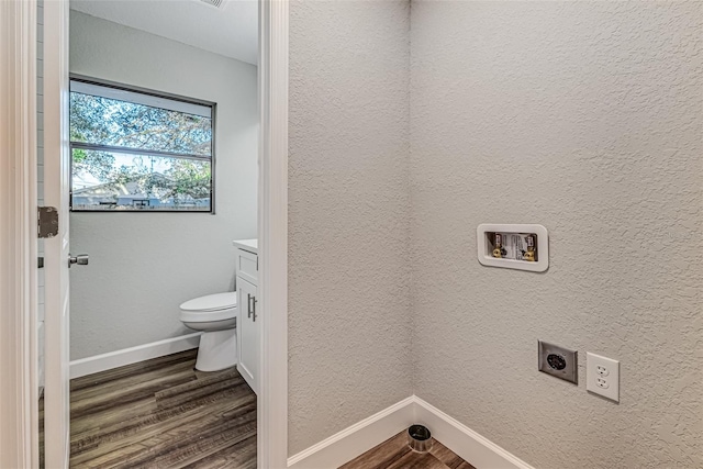 bathroom with a textured wall, toilet, wood finished floors, vanity, and baseboards