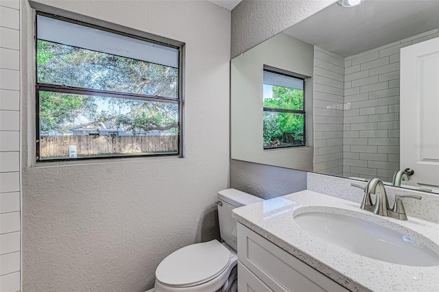 bathroom with toilet, a textured wall, and vanity