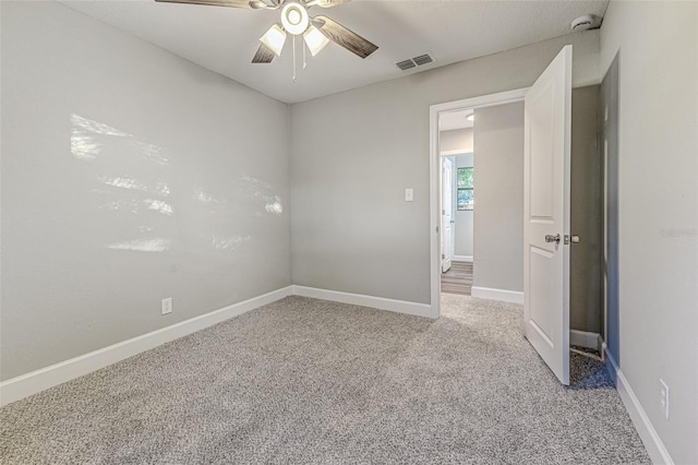 spare room with carpet, visible vents, ceiling fan, and baseboards