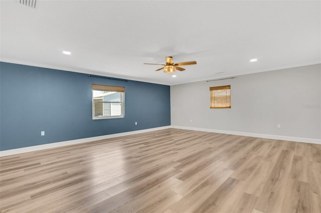 empty room with light wood-style floors, crown molding, and baseboards