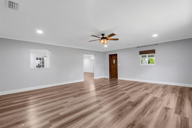 unfurnished room featuring light wood finished floors, visible vents, baseboards, a ceiling fan, and ornamental molding