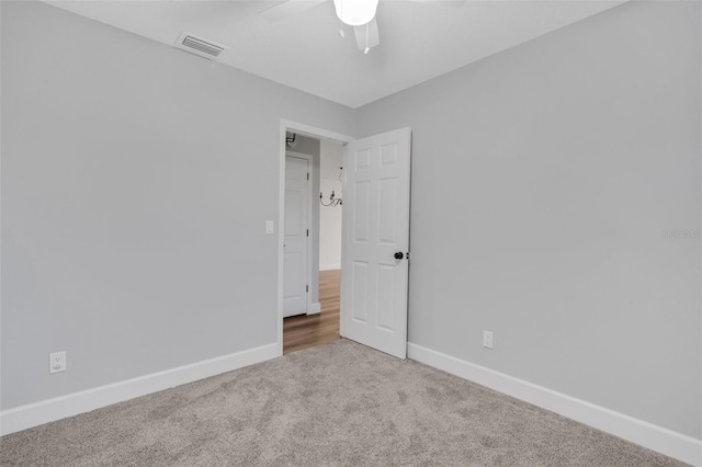 carpeted empty room with baseboards, visible vents, and ceiling fan