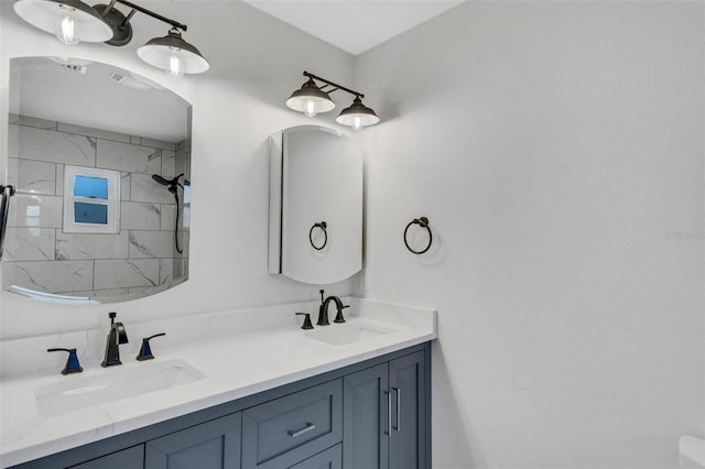 bathroom with a sink, a tile shower, and double vanity