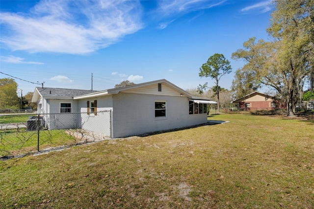 exterior space featuring a yard, brick siding, and fence