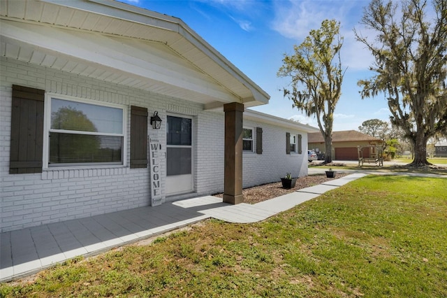 property entrance featuring a yard and brick siding