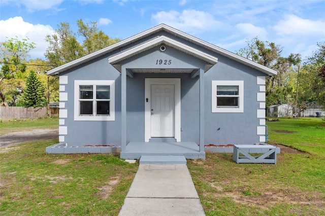 view of front facade with fence, a front lawn, and stucco siding