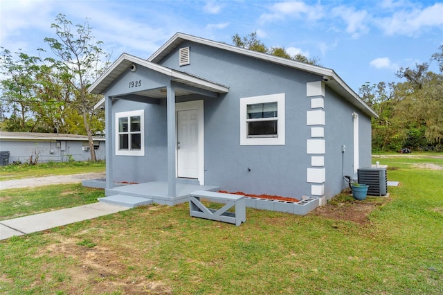 bungalow-style home featuring a front lawn, cooling unit, and stucco siding